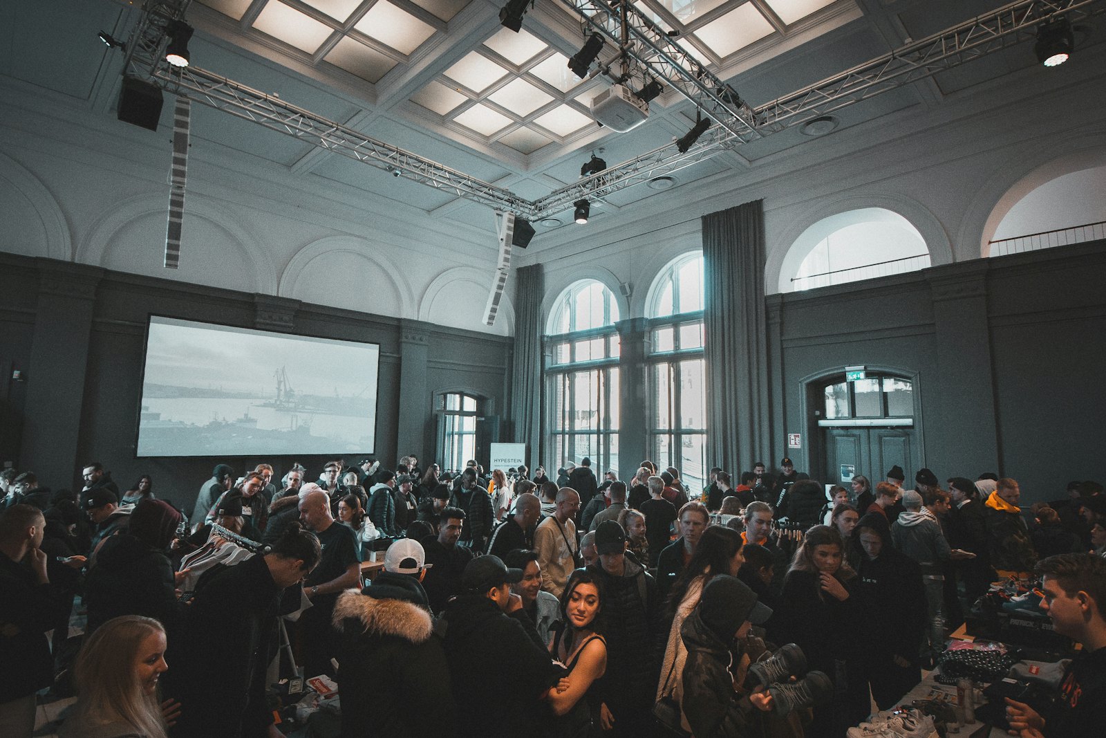A crowded expo floor inside a venue hall, attendees moving between exhibitor tables